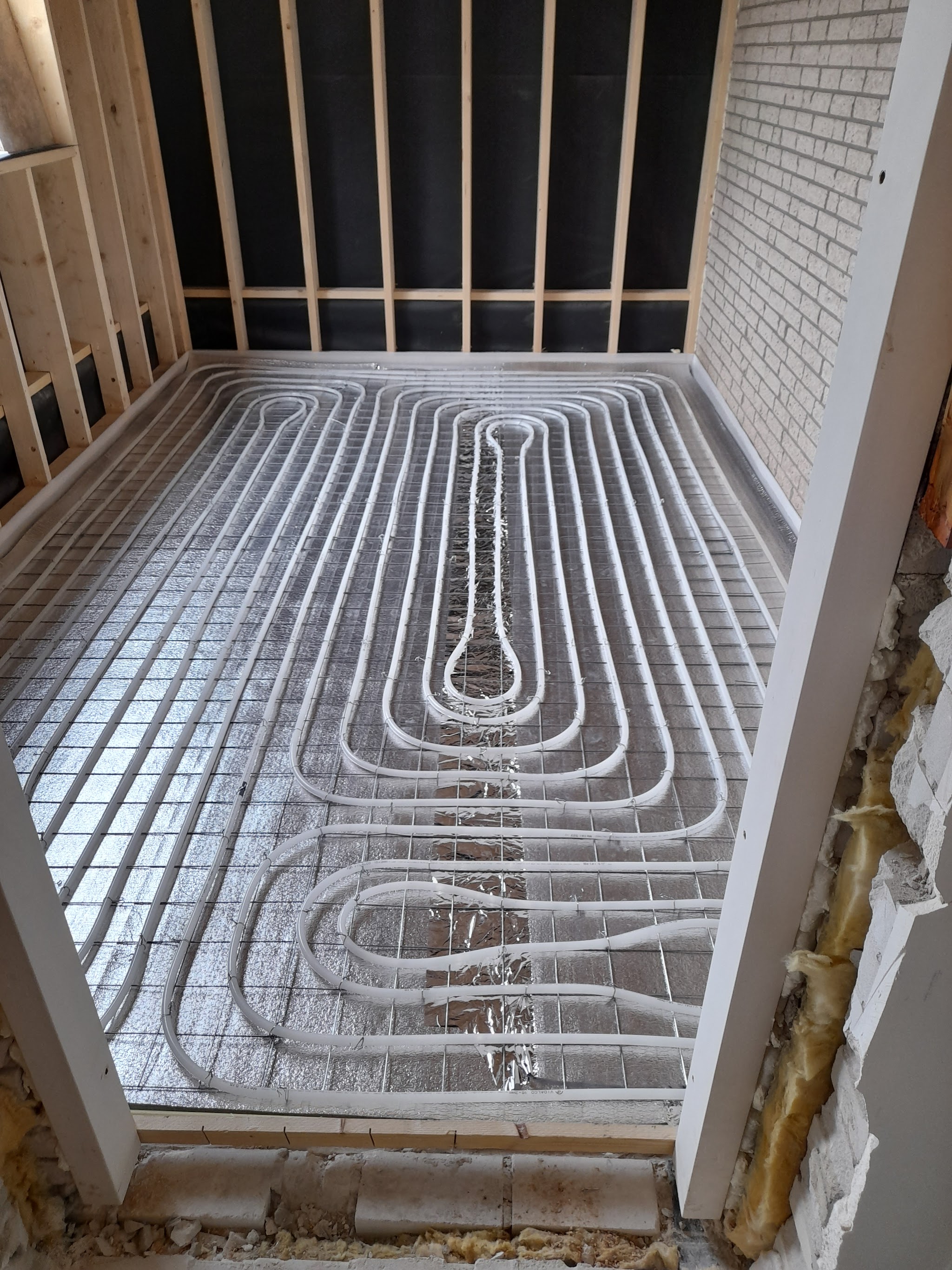 Witte buizen op noppenplaten in een nieuwe aanbouw tussen houten stijlwanden